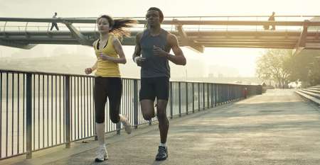 Man and woman jogging along riverbank