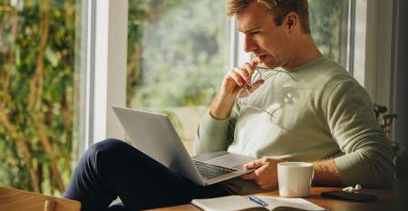Man sitting in chair at home with laptop