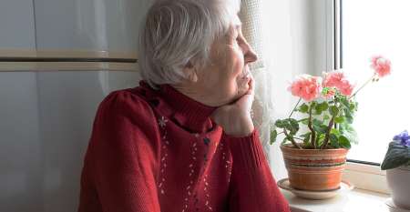 Older woman sitting in kitchen looking out window