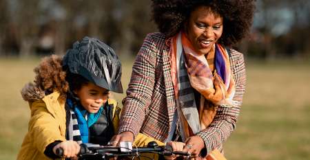 Woman helping child ride bike