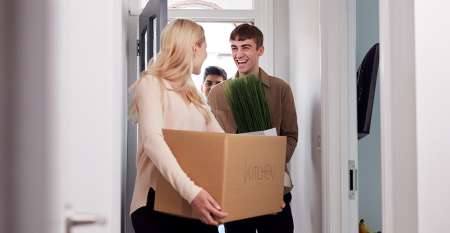 Young people carrying boxes into new home