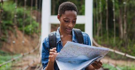 Woman in rural surroundings looking at travel map on bridge