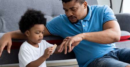 Young son at home holding father's hand