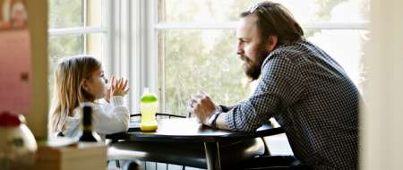 Man and young girl talking at a table