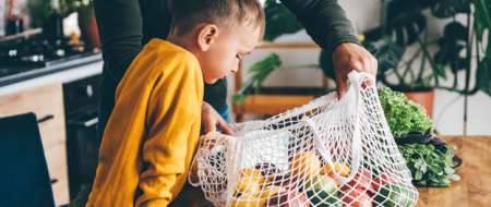 Young boy looking at fruit in a string bag
