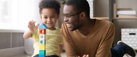 Man and young baby boy building tower using blocks